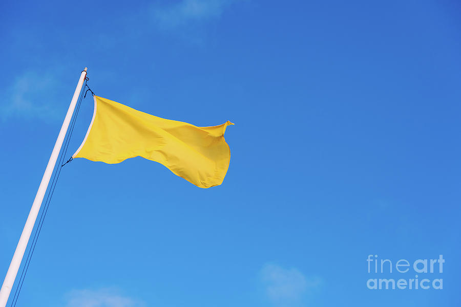 Yellow warning flag on a beach against the blue sky background. Photograph by Joaquin Corbalan