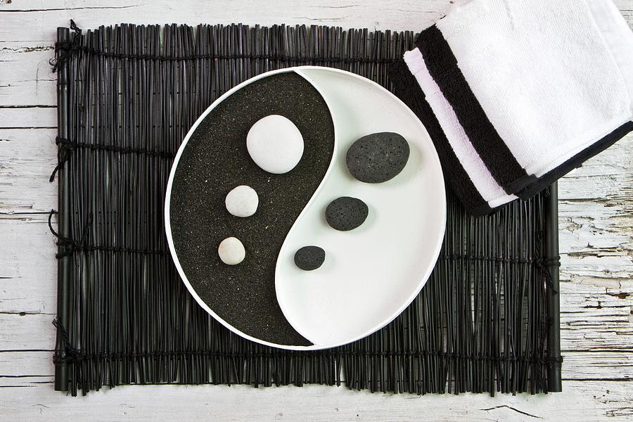 Yin And Yang Dish With Black Pumice And White Pebbles On Bamboo Mat Photograph by Uwe Merkel