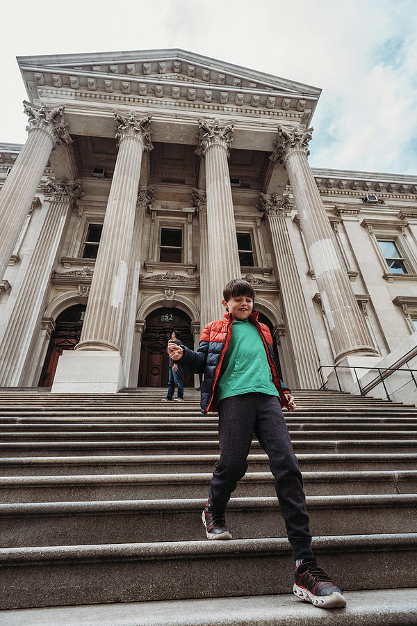 Architecture Photograph - Young Boy Running Down Steps Of A Big Stone Building In New York City. by Cavan Images