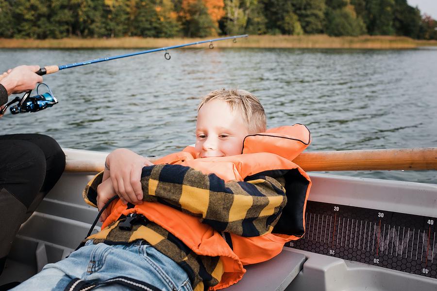 Young Boy Sat Relaxing On A Boat Whilst Out On A Boat Fishing ...