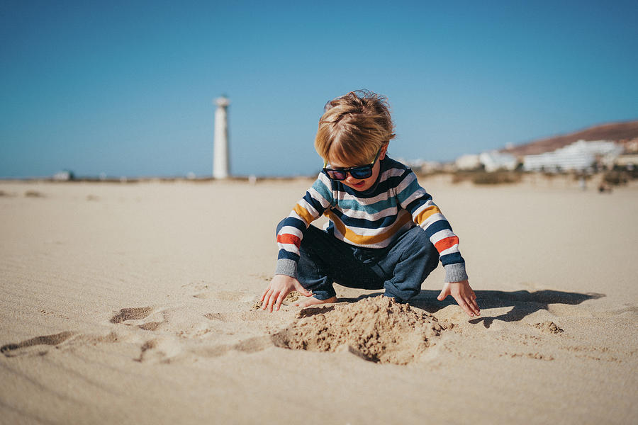Canary Photograph - Young Boy Wearing Sunglasses Playing With Sand At Beach by Cavan Images