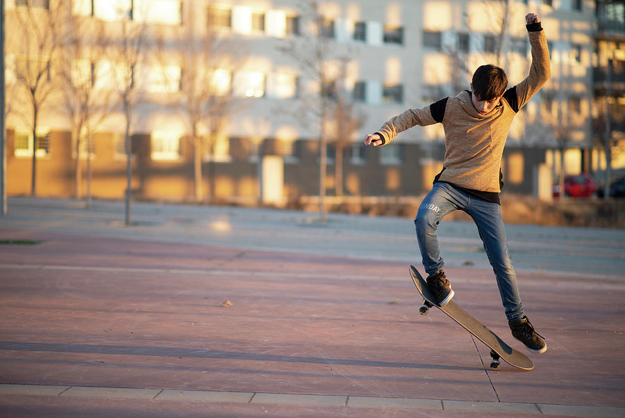Cool Photograph - Young Caucasian Teen With Red Hut Jumping On A Skateboard In The City by Cavan Images