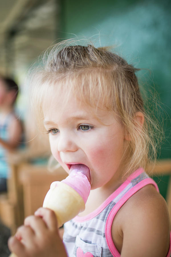 Young Cute Girl Happily Licking Pink Ice Cream On Summer Day 