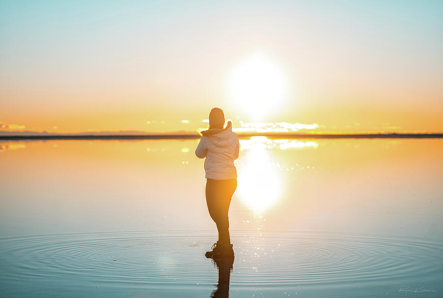 Young female standing on water admiring the sunrise. Photograph by Ryan Kelehar