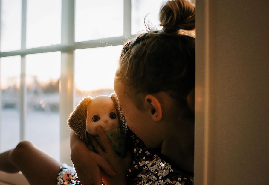 Sunset Photograph - Young Girl Cuddling Her Toy At Home At Sunset In Sweden by Cavan Images