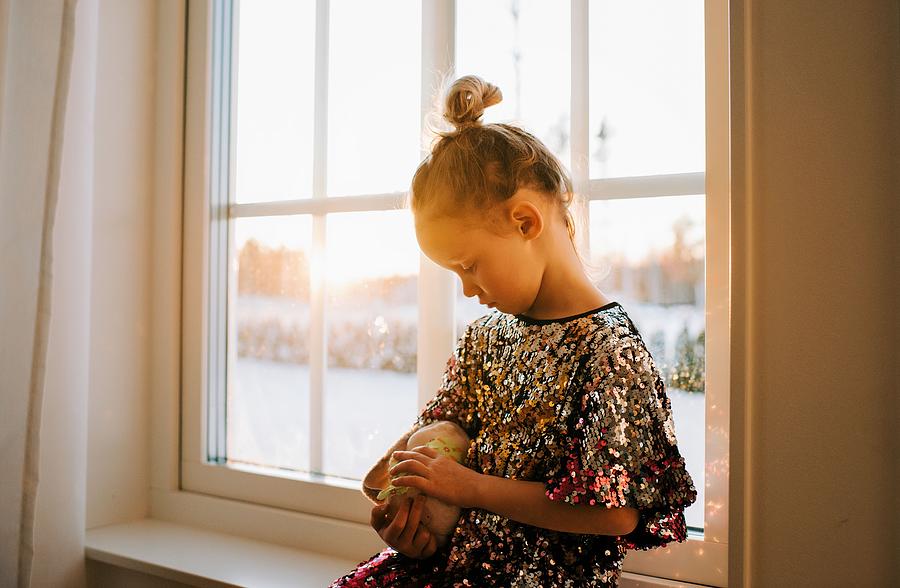 Sunset Photograph - Young Girl Cuddling Her Toy In A Sparkly Dress At Home At Sunset by Cavan Images