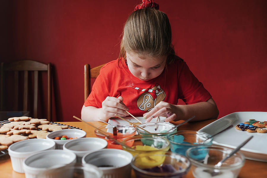 Christmas Photograph - Young Girl Decorating Gingerbread Cookies On A Wooden Table by Cavan Images