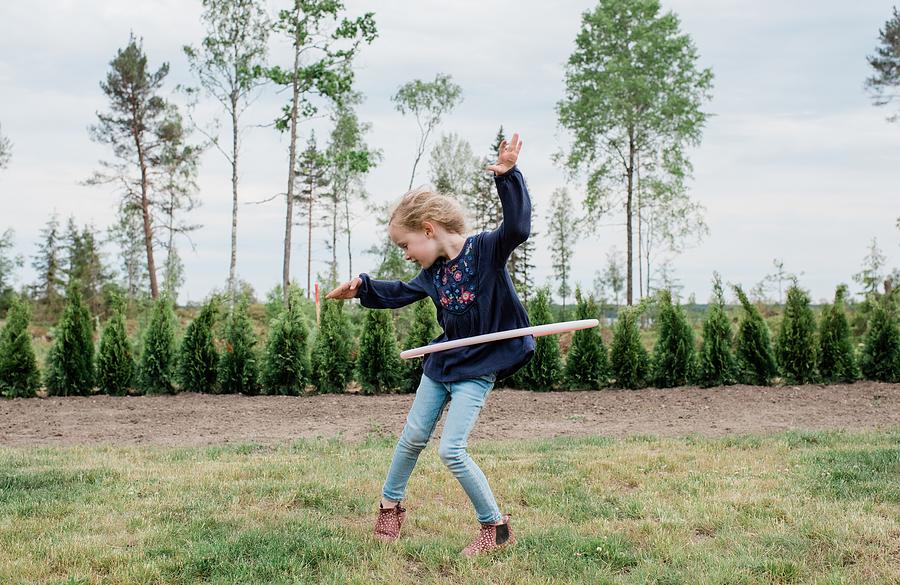 Daisy Photograph - Young Girl In Her Garden Playing With A Hula Hoop by Cavan Images