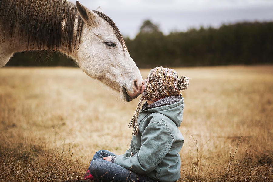 Fall Photograph - Young Girl Kisses White Horse On Nose While Sitting On Ground by Cavan Images