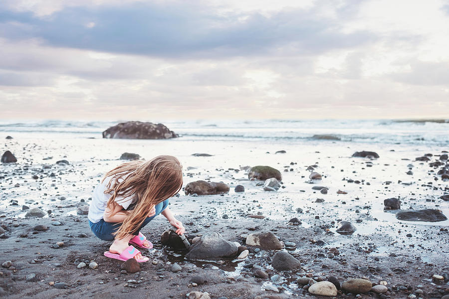 Young Girl Looking Under Rocks At The Beach Photograph by Cavan Images ...