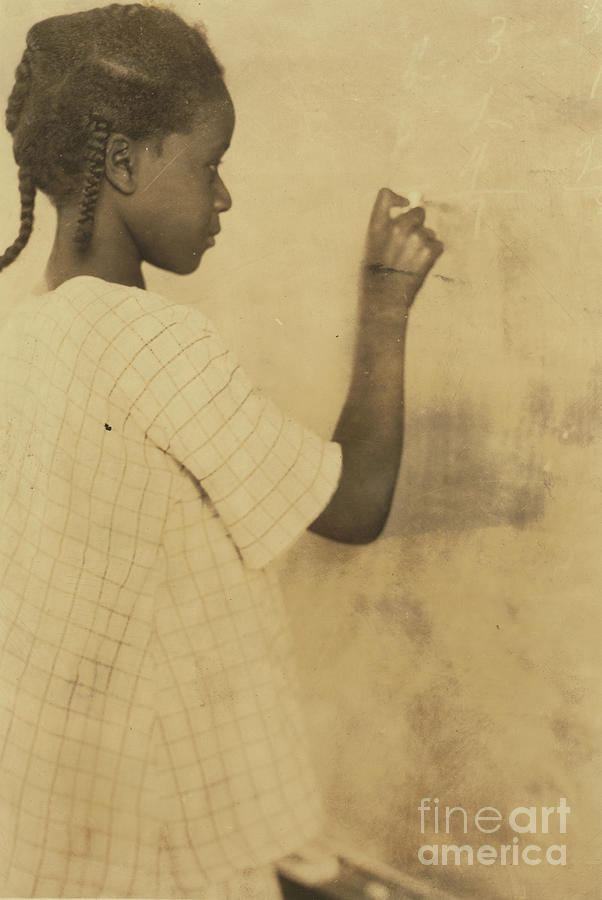 Young Girl Writing On Chalkboard In Classroom Photograph by Unknown
