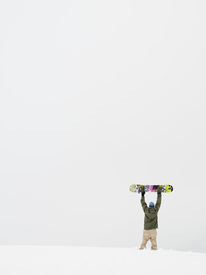 Young Man Holding Snowboard Above Head Photograph by Thomas Barwick