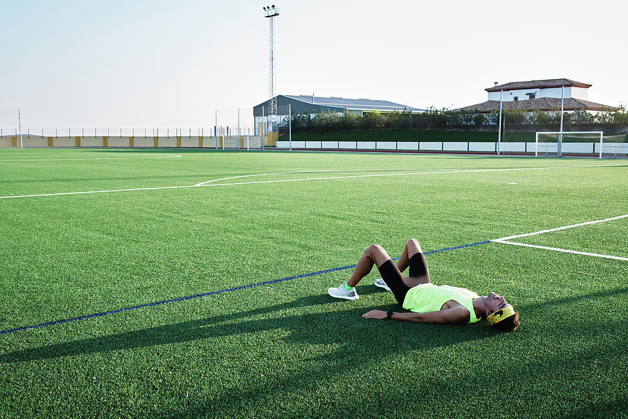 Summer Photograph - Young Man Rests On The Grass Of A Soccer Field After Training by Cavan Images