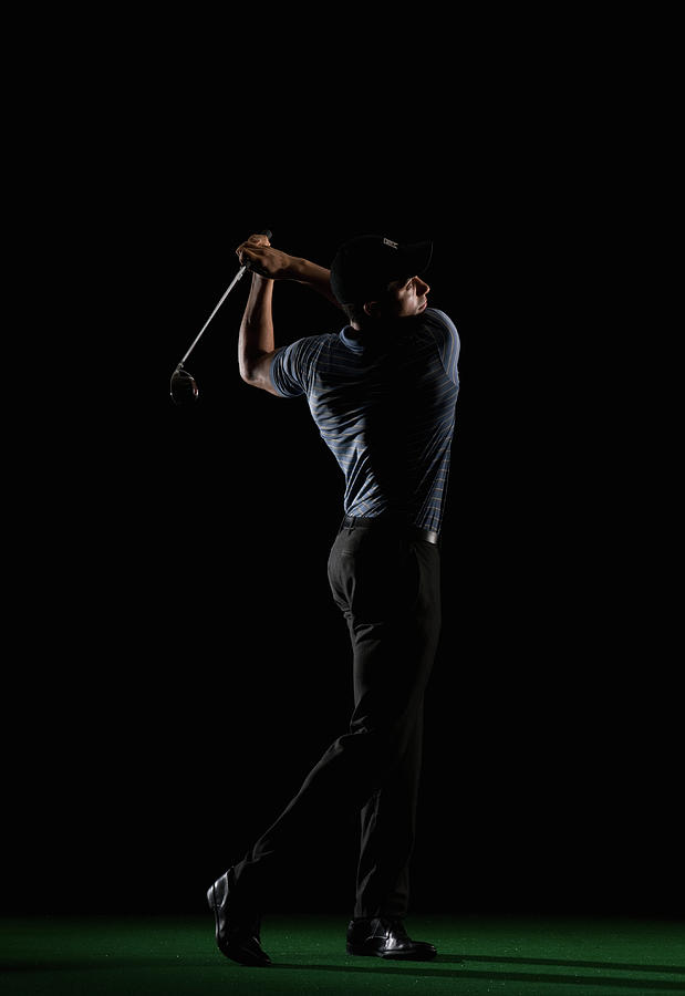 Young Man Swinging Golf Club Photograph by Pm Images