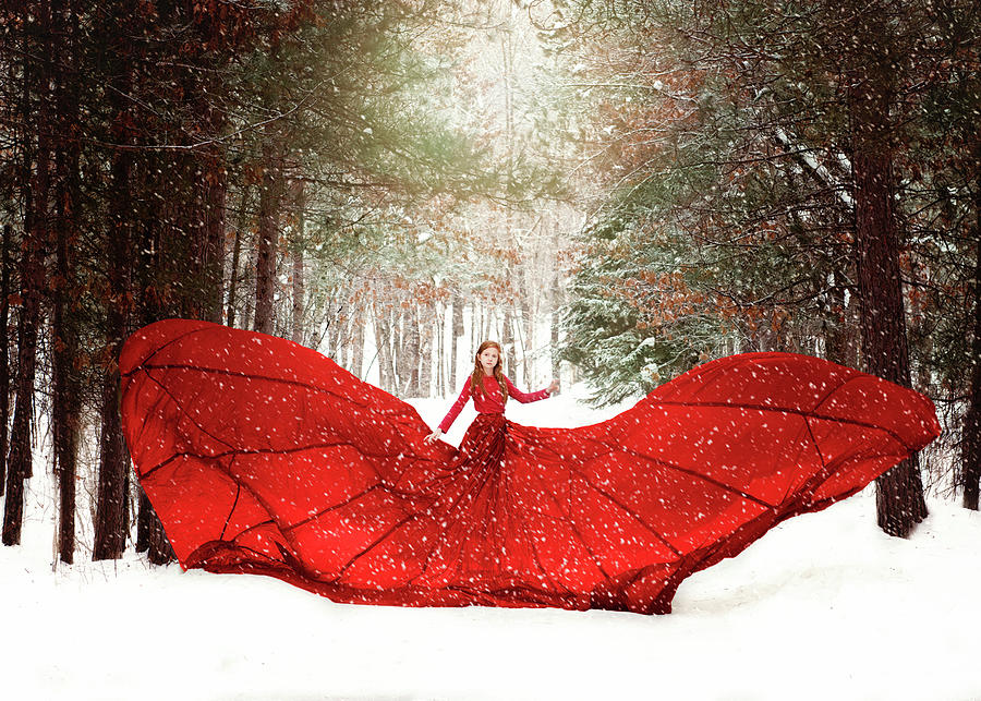 Young Redhead Girl In Flowing Red Dress In Forest With Snowfall