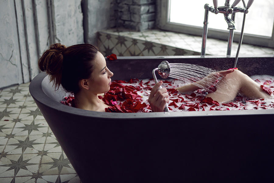 Young Sexy Beautiful Woman Lies In A Stone Bath With Petals Photograph