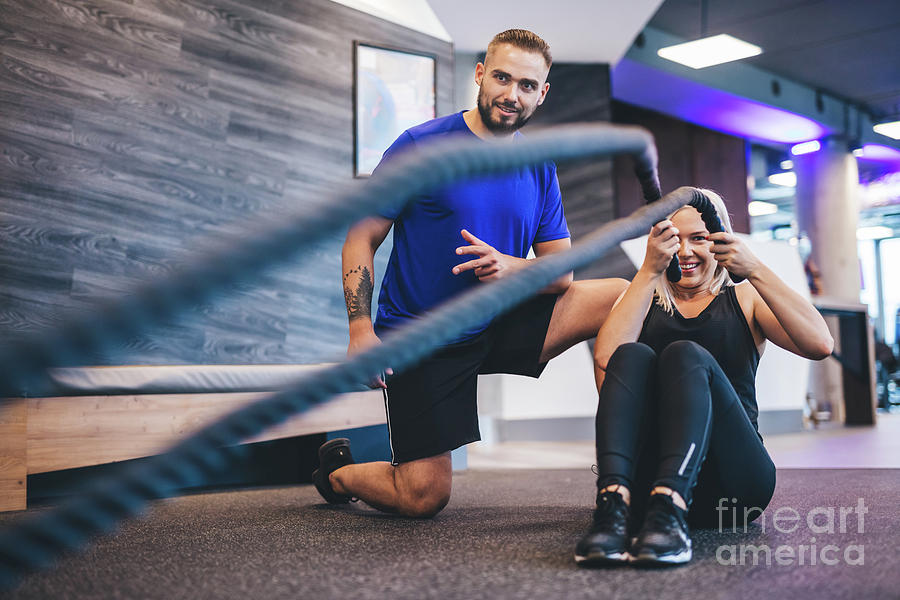 Young woman exercising with personal trainer at the gym. Photograph by Michal Bednarek