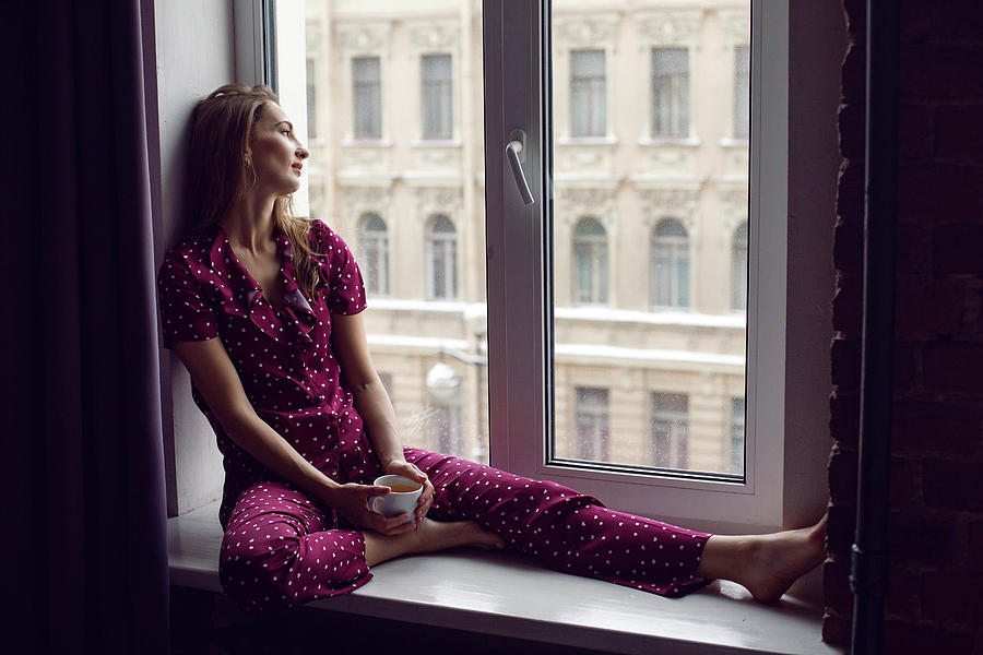Young Woman In Red Pajamas Sitting In The Morning On The Windowsill Photograph