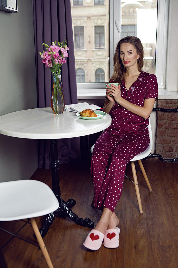 young woman in red pajamas with polka dots sitting at Breakfast Photograph