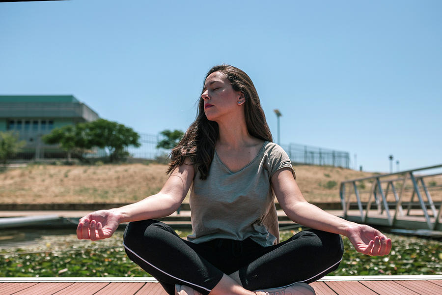 Young Woman Is Meditating On The Footbridge Of A Jetty Photograph by ...