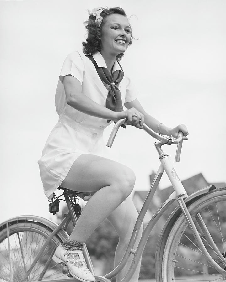 Black And White Photograph - Young Woman Riding Bicycle, B&w, Low by George Marks