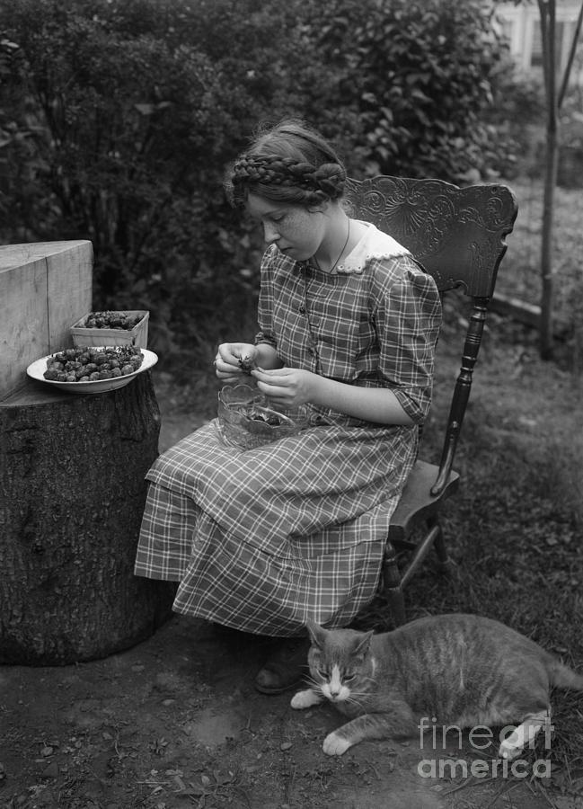 Young Woman Stoning Prunes With Cat Photograph by Bettmann