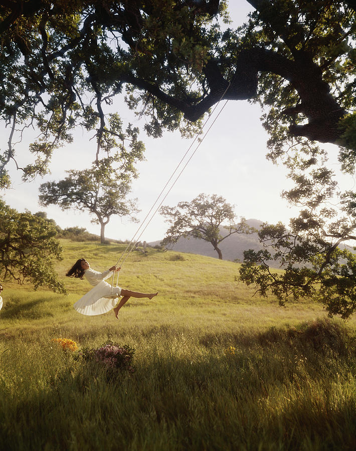 Young Woman Swinging On Rope Swing Tied Photograph by Tom Kelley Archive