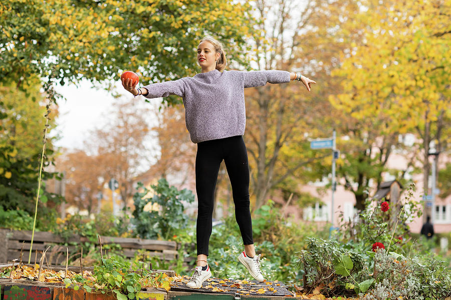 Tree Photograph - Young Woman With Blond Hair Standing With Pumpkin In An Urbanic Garden by Cavan Images