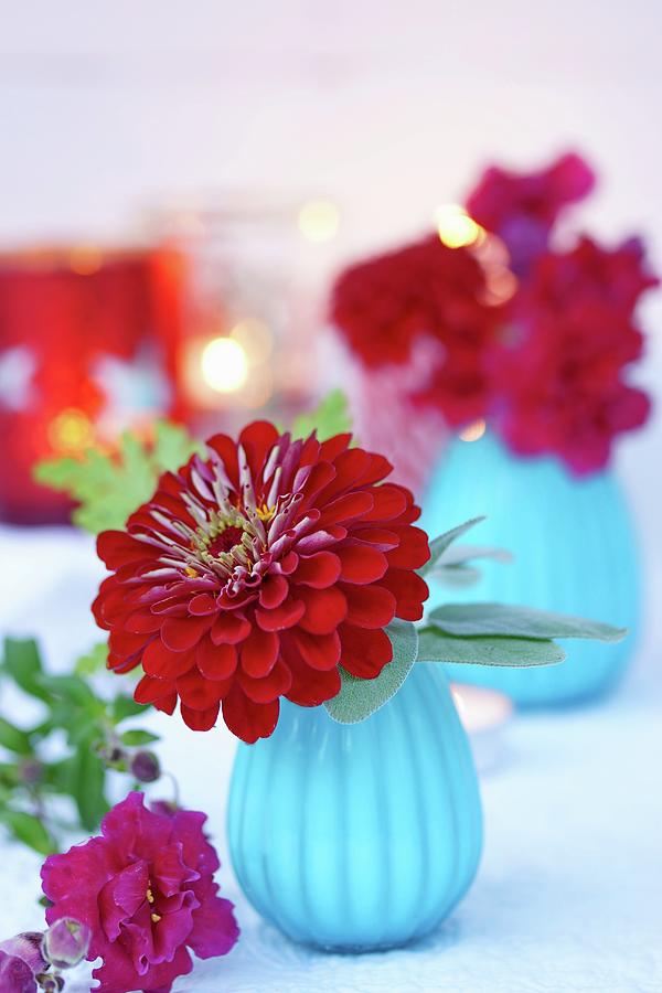 Zinnia And Snap Dragons In Turquoise Glass Vases With Lit Candles In Background Photograph by Angelica Linnhoff