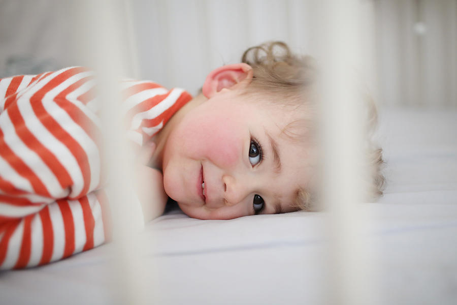 A 2 years old boy waking up from his nap in his bed #1 Photograph by Catherine Delahaye