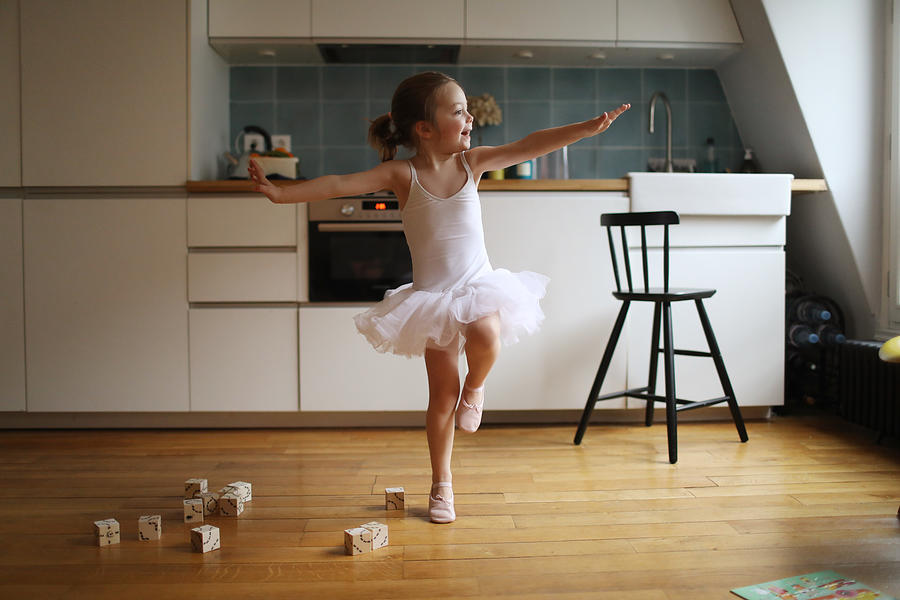 A 4 years old girl dressed as a dancer, dancing in the kitchen #1 Photograph by Catherine Delahaye