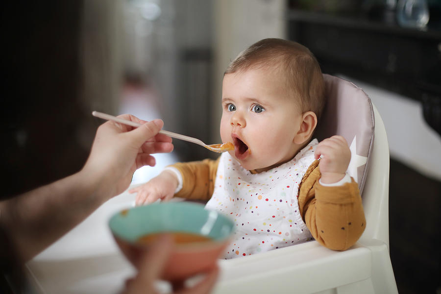 A 6 months old baby girl taking her meal #1 Photograph by Catherine Delahaye