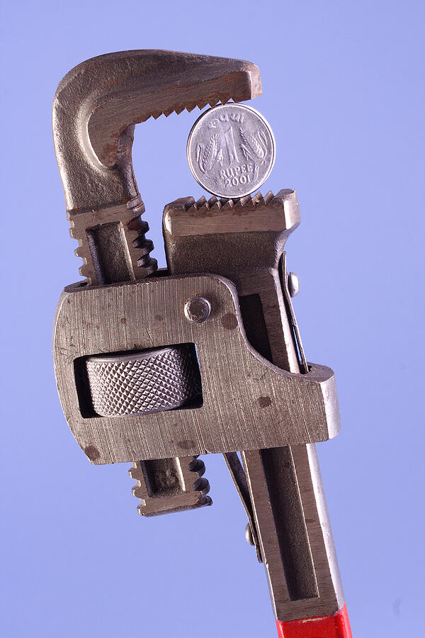 A coin held by a wrench #1 Photograph by Visage