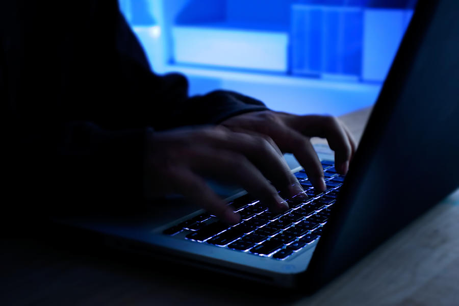 A computer programmer or hacker prints a code on a laptop keyboard to break into a secret organization system. Internet crime concept. #1 Photograph by Rapeepong Puttakumwong