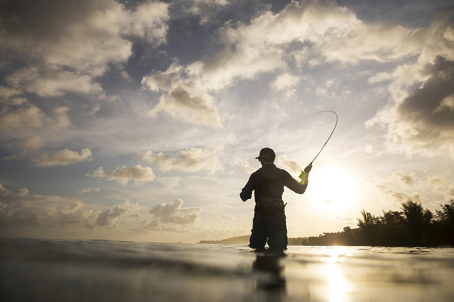 A man fly fishing in the ocean. #1 Photograph by Jordan Siemens
