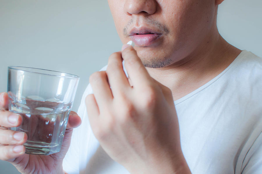 A man is drinking a medicine pill #1 Photograph by Karl Tapales