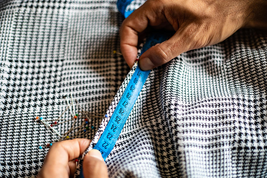 A mans hands measuring the textile with tape measure. Sewing items; fabric, tape measure, ball head sewing needles. #1 Photograph by Photographer, Basak Gurbuz Derman