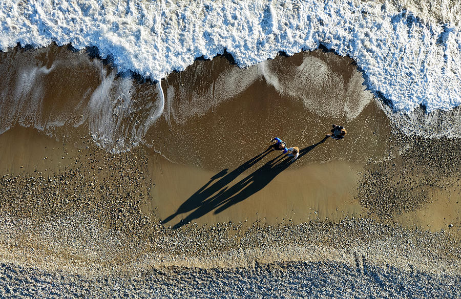 Aerial seascape of person walking in a beach. Stormy waves idyllic beach in winter. #1 Photograph by Michalakis Ppalis