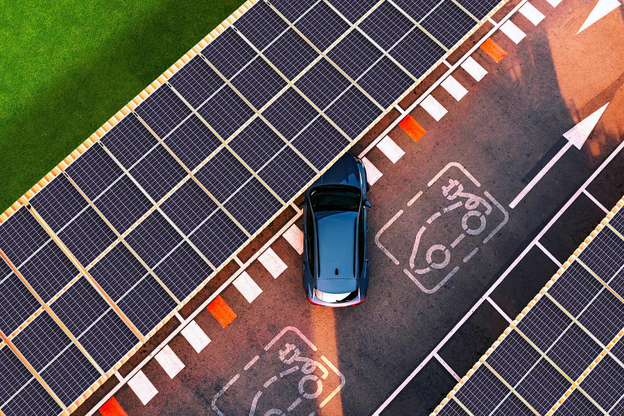 Aerial view of electric car parking in charging station with solar panels. #1 Photograph by Artur Debat