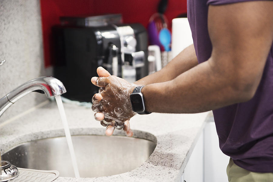 African-American man washing hands in kitchen sink. #1 Photograph by Martinedoucet