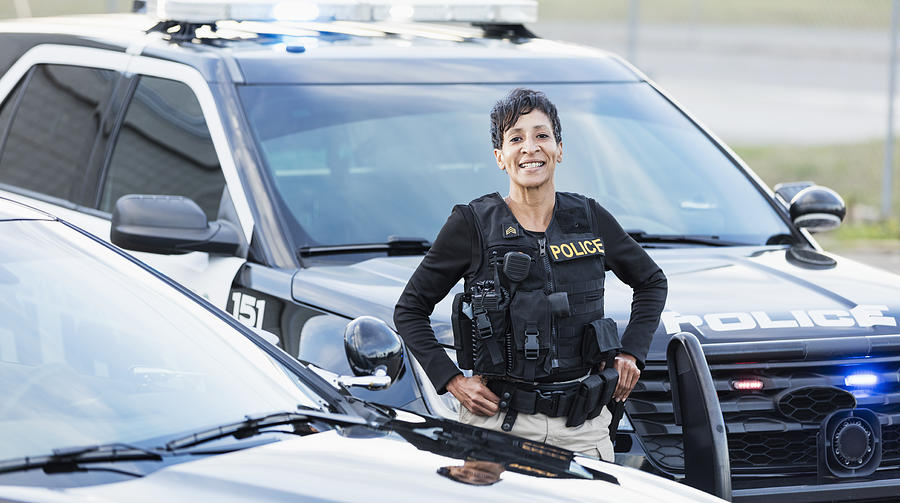 African-American policewoman standing by patrol car Photograph by Kali9