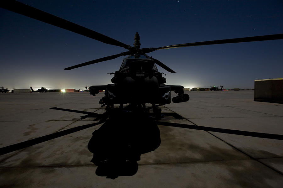 An AH-64 Apache waits on the flight line at night at Camp Speicher. #1 Photograph by Stocktrek Images