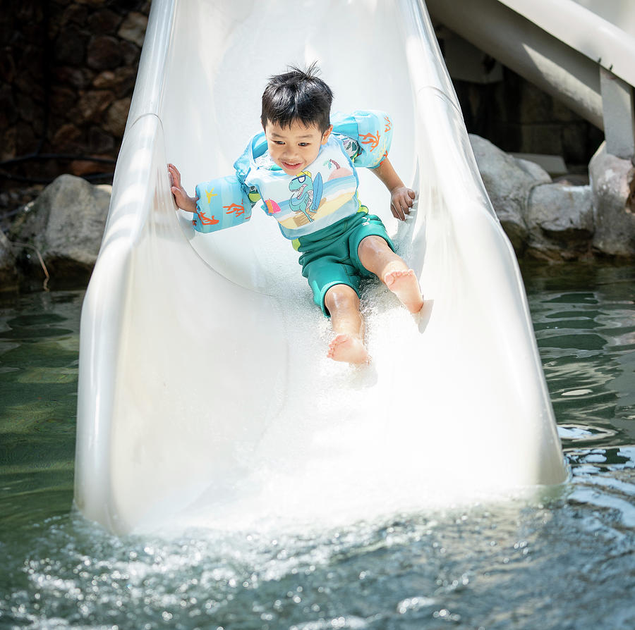 Asian boy play on the  slider water #1 Photograph by Anek Suwannaphoom
