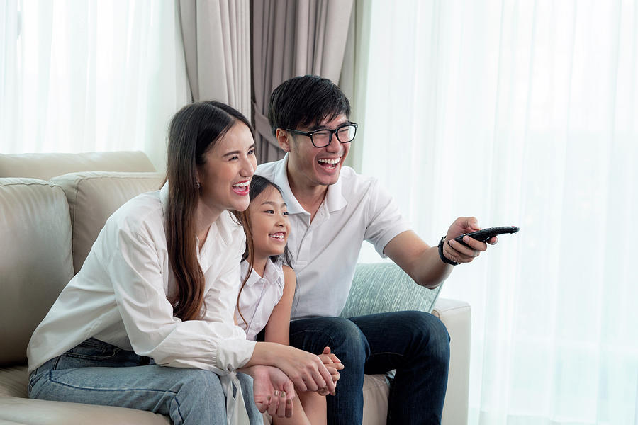 Asian family enjoy looking lcd tv on sofa in living room Photograph by ...