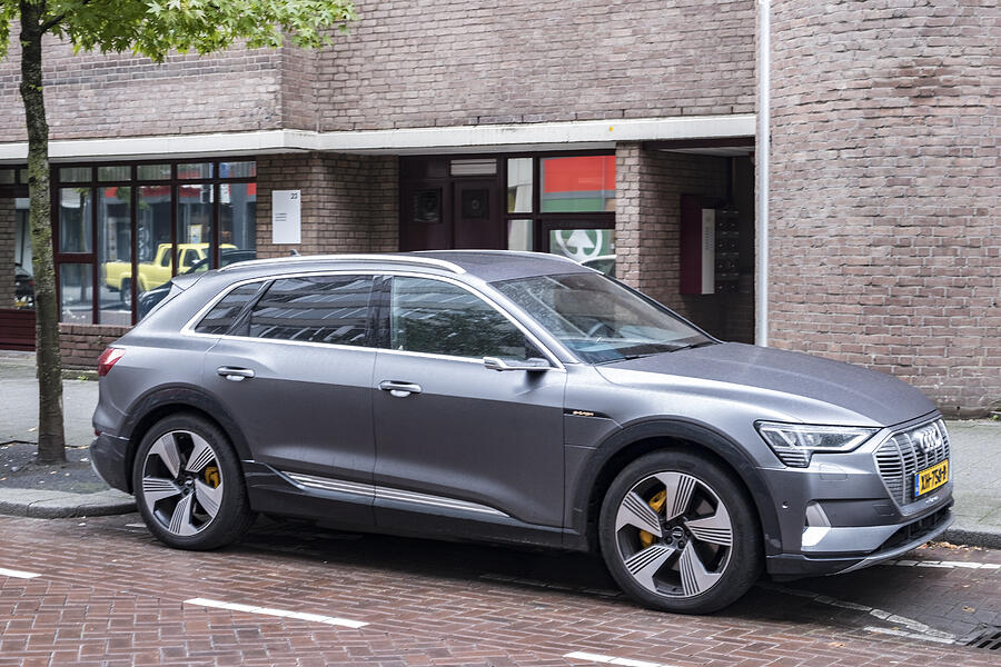 Audi e-tron 55 quattro electric SUV at an electric vehicle charging station in the city #1 Photograph by Sjo