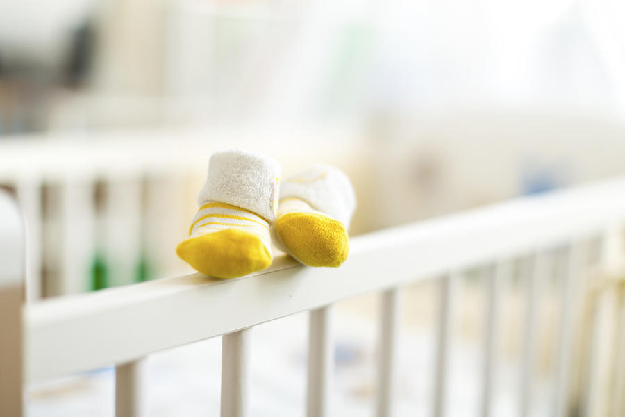 Baby booties on the edge of a cot #1 Photograph by Wladimir Bulgar/science Photo Library