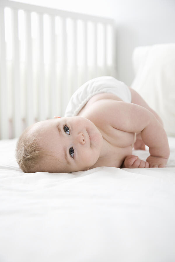 Baby girl (6-9 months) laying on bed.  #1 Photograph by Steven Errico