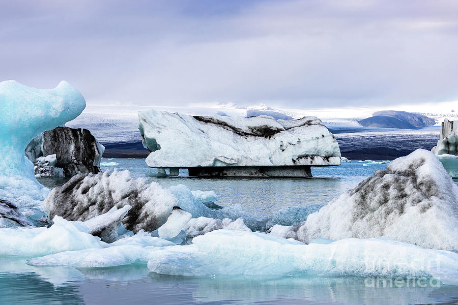 Beautiful blue icebergs reflected in the Jokulsarlon glacial lag #1 Photograph by Jane Rix
