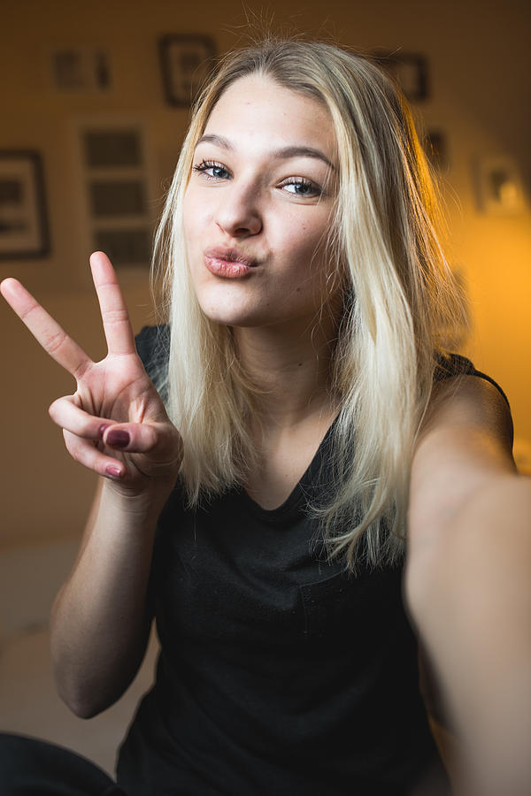 Beautiful Cheerful Teenage Girl Taking a Selfie in Bedroom #1 Photograph by CasarsaGuru