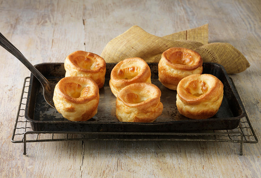 Beef dripping Yorkshire puddings on metal baking tray and wire rack #1 Photograph by Diana Miller
